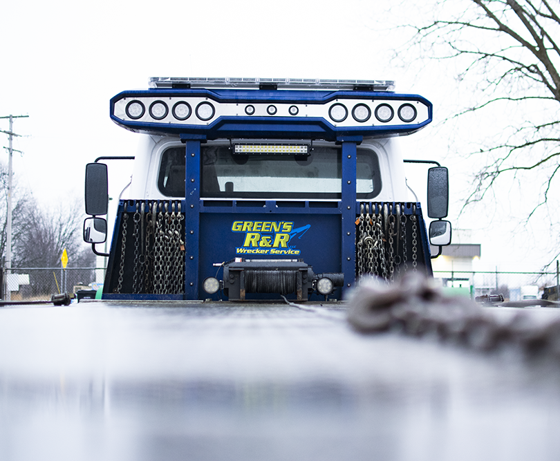 The back of a flatbed tow truck that says Green's R&R Wrecker Service.